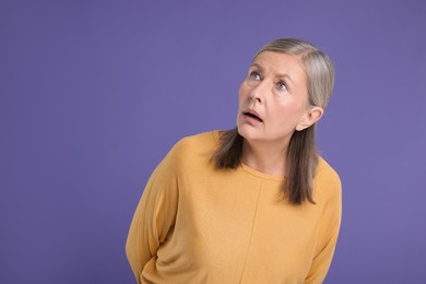 Photo of Portrait of surprised senior woman on violet background, space for text