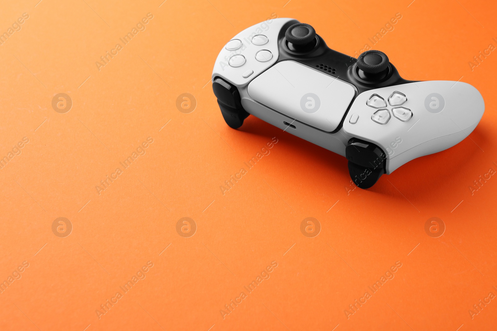 Photo of One wireless game controller on orange background. Space for text