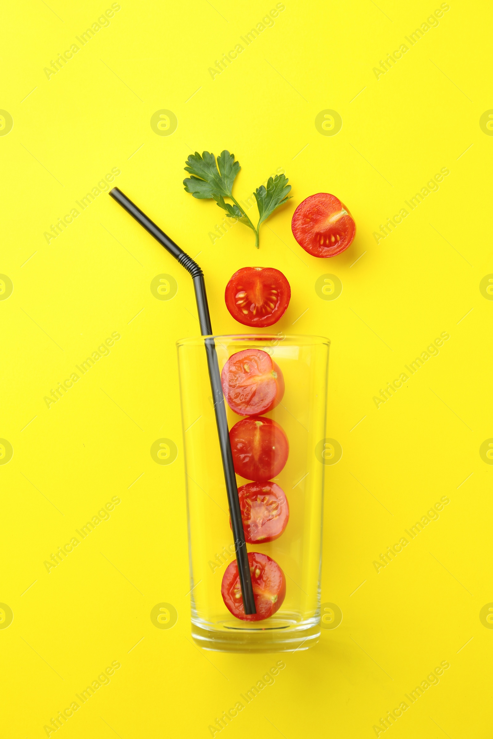 Photo of Glass, fresh tomatoes, parsley and straw on yellow background, flat lay