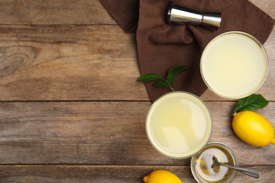 Delicious bee's knees cocktails and ingredients on wooden table, flat lay. Space for text