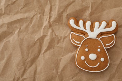 Photo of Christmas deer shaped gingerbread cookie on crumpled parchment, top view. Space for text