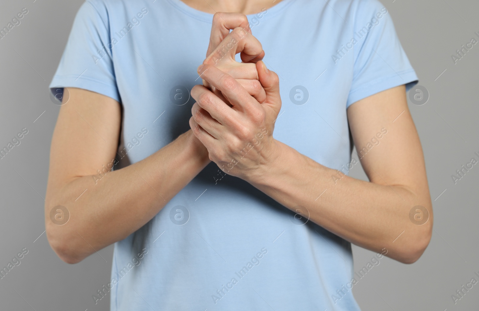 Photo of Woman cracking her knuckles on light grey background, closeup. Bad habit