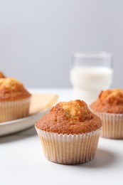 Photo of Delicious sweet muffins on white table, closeup. Space for text