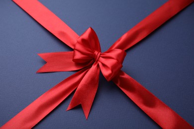 Photo of Red satin ribbon with bow on blue background