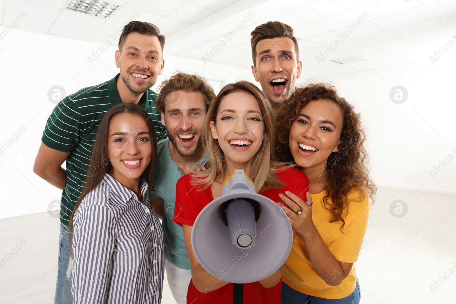 Photo of Group of happy young people with megaphone indoors