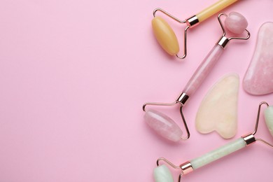 Photo of Different gua sha stones and face rollers on pink background, flat lay. Space for text