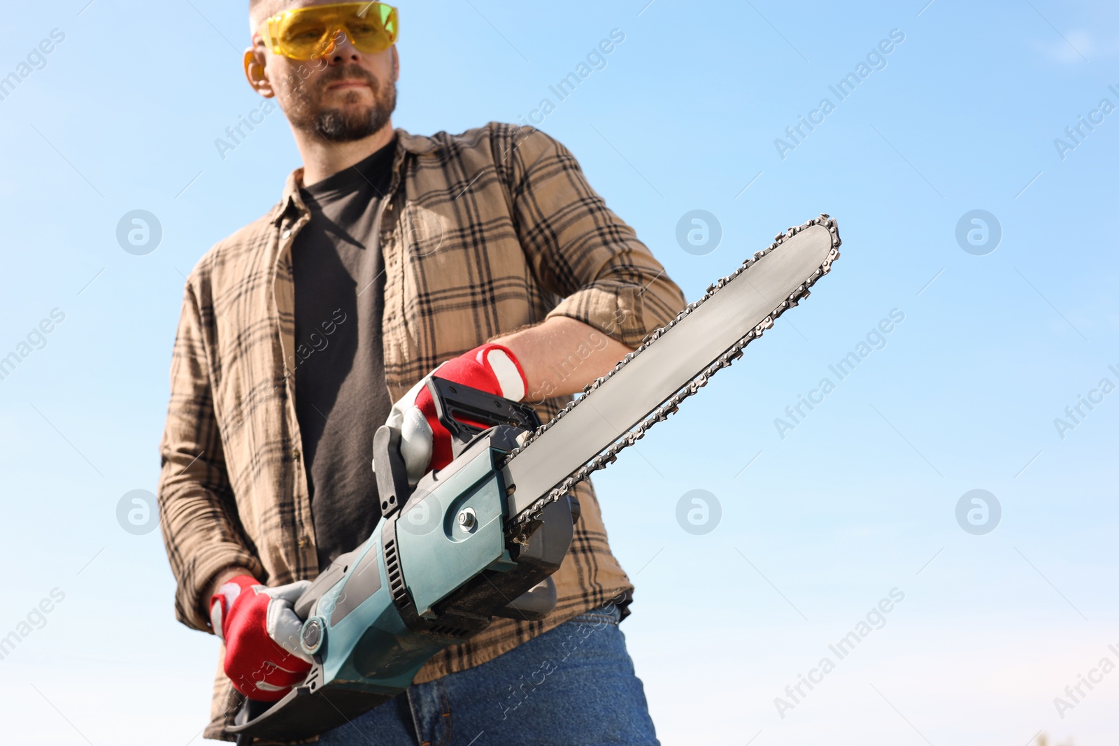 Photo of Man with modern saw against blue sky, low angle view