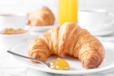 Photo of Tasty breakfast. Fresh croissant and jam on white marble table, closeup