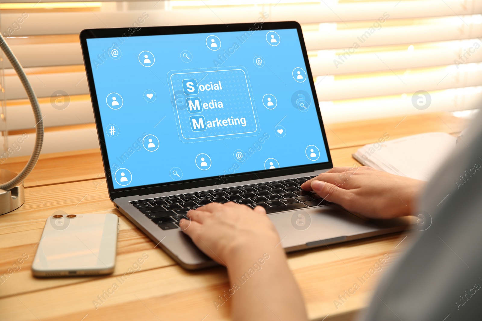 Image of SMM (Social Media Marketing) concept. Woman working with modern laptop at wooden table, closeup