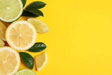 Photo of Fresh ripe lemons, limes and green leaves on yellow background, flat lay. Space for text