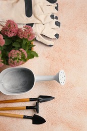 Flat lay composition with watering can and gardening tools on color textured background