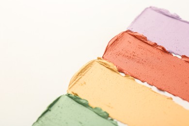 Photo of Samples of different color correcting concealers on white background, closeup