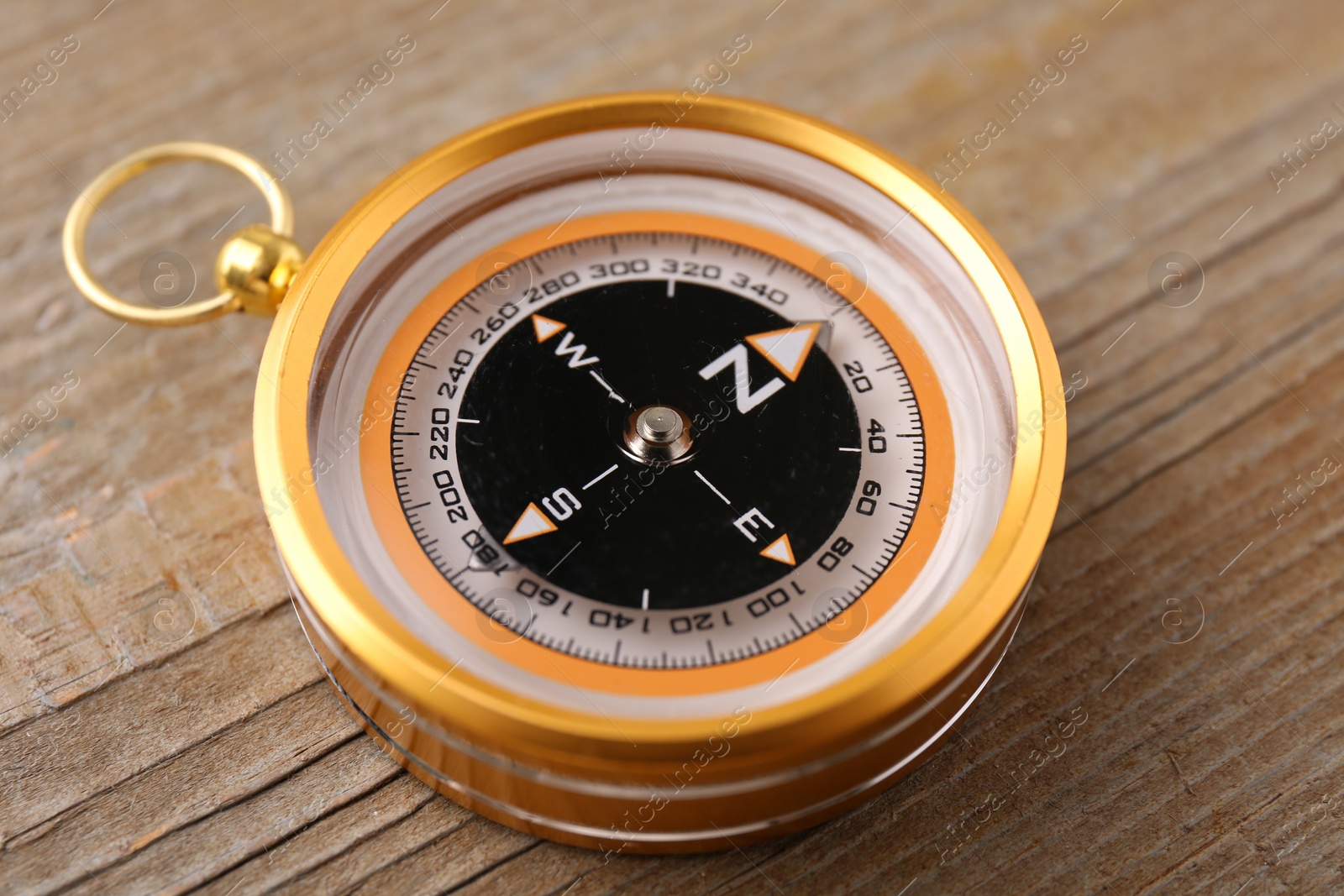 Photo of One compass on wooden table, closeup. Navigation equipment