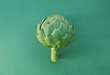 Photo of Whole fresh raw artichoke on green background