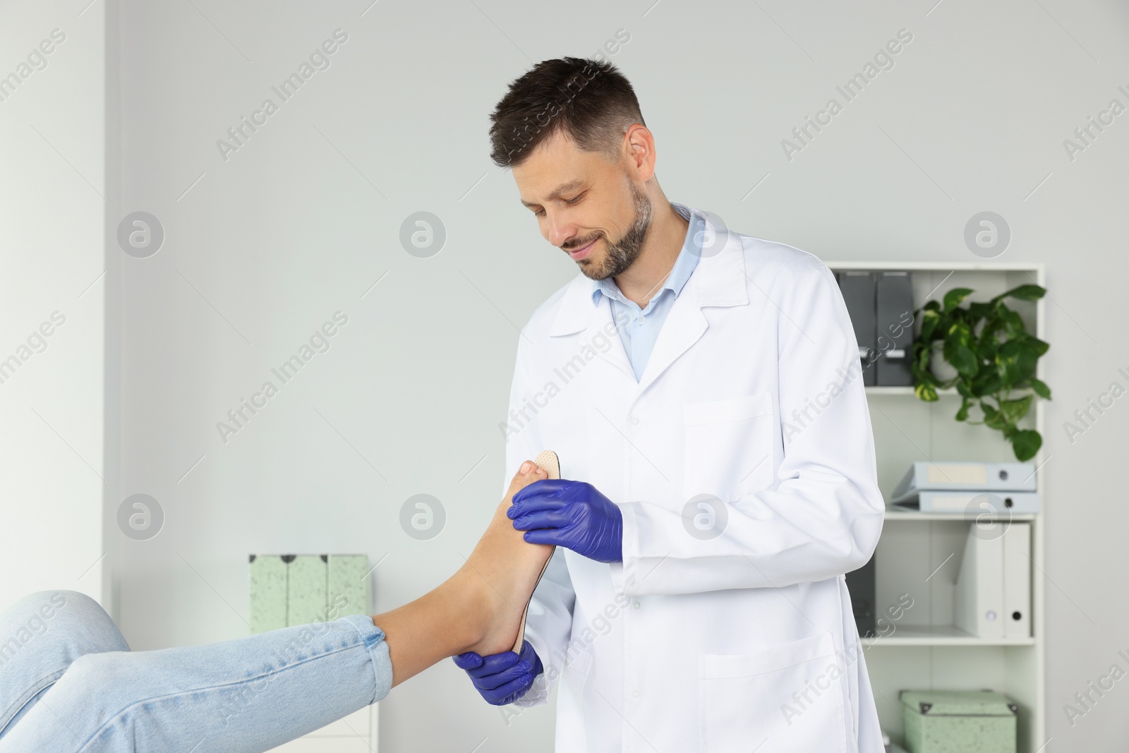 Photo of Male orthopedist fitting insole to patient's foot in hospital