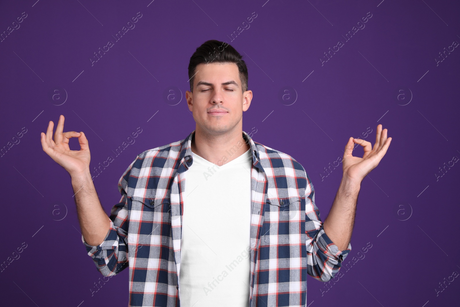 Photo of Man meditating on purple background. Stress relief exercise