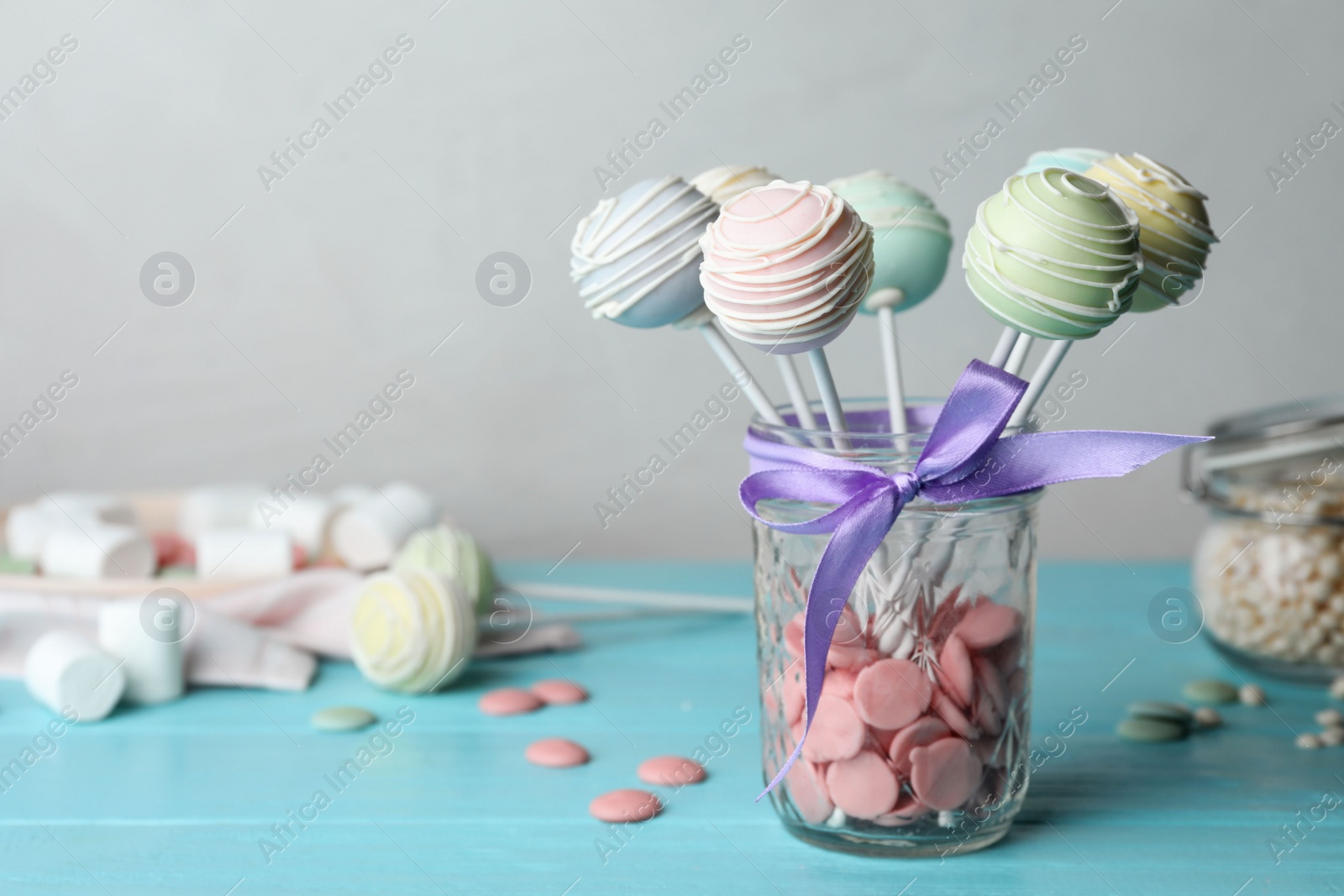 Photo of Sweet cake pops on light blue wooden table against grey background. Space for text