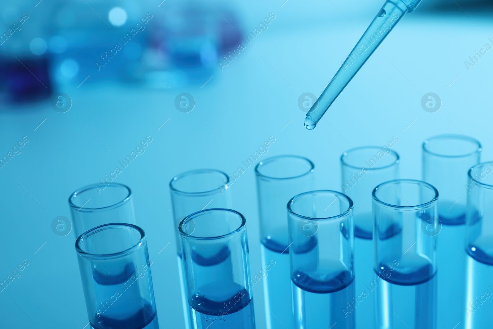 Photo of Dripping reagent into test tube with blue liquid, closeup. Laboratory analysis