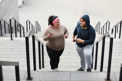 Photo of Overweight couple running up stairs together outdoors