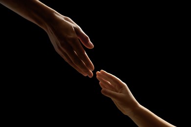 Photo of Woman with child on black background, closeup of hands