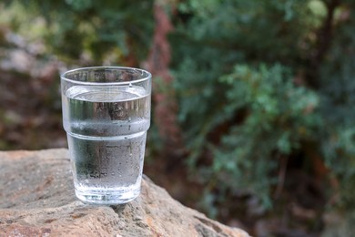 Photo of Glass of water on stone outdoors, space for text