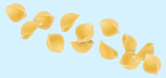 Raw conchiglie pasta flying on light blue background