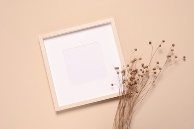 Photo of Empty photo frame and dry decorative flowers on beige background, flat lay. Space for design