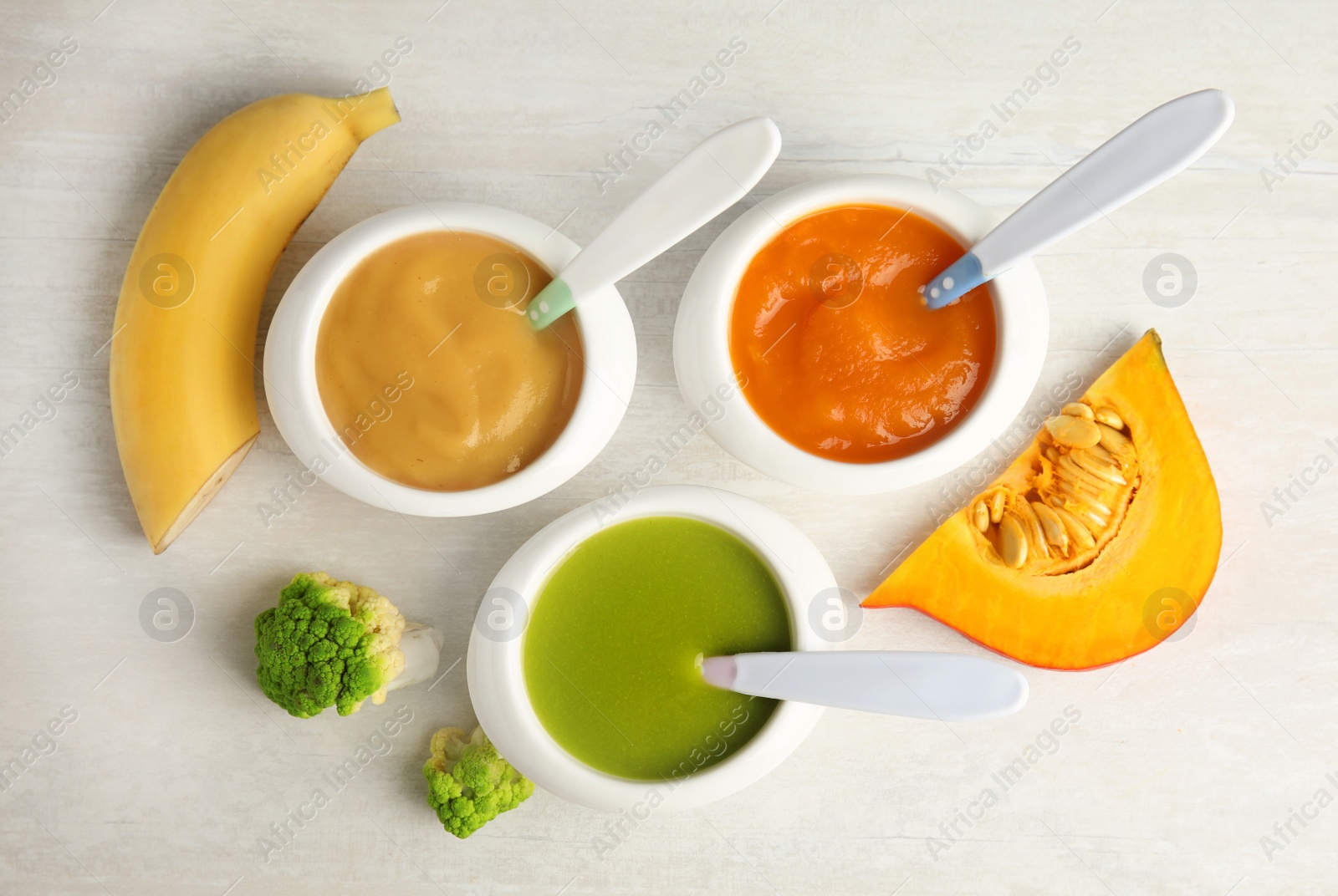 Photo of Bowls with different baby food on light background, flat lay