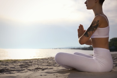 Photo of Young woman practicing zen meditation on beach, closeup. Space for text
