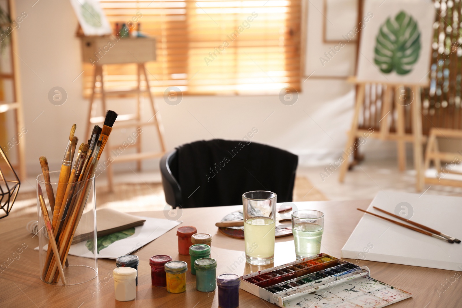 Photo of Paints and brushes on wooden table in art studio