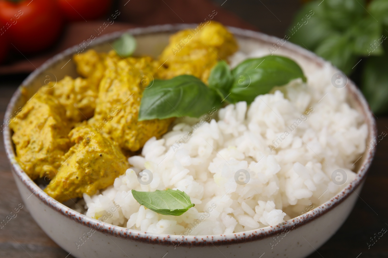 Photo of Delicious rice and chicken with curry sauce in bowl, closeup