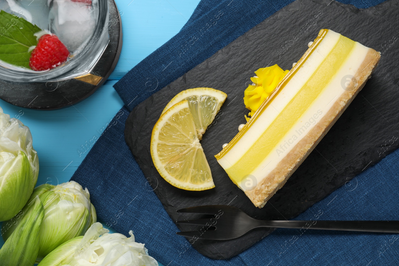 Photo of Delicious cheesecake with lemon and peonies on light blue wooden table, flat lay