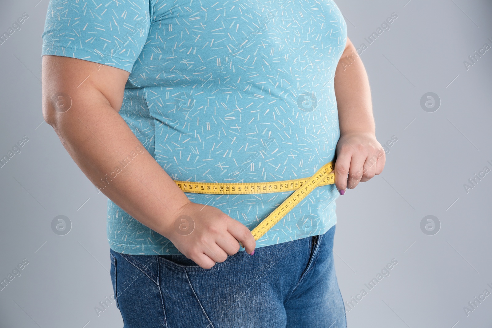 Photo of Overweight woman measuring waist before weight loss on color background