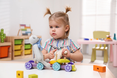 Photo of Little girl playing with toys at table