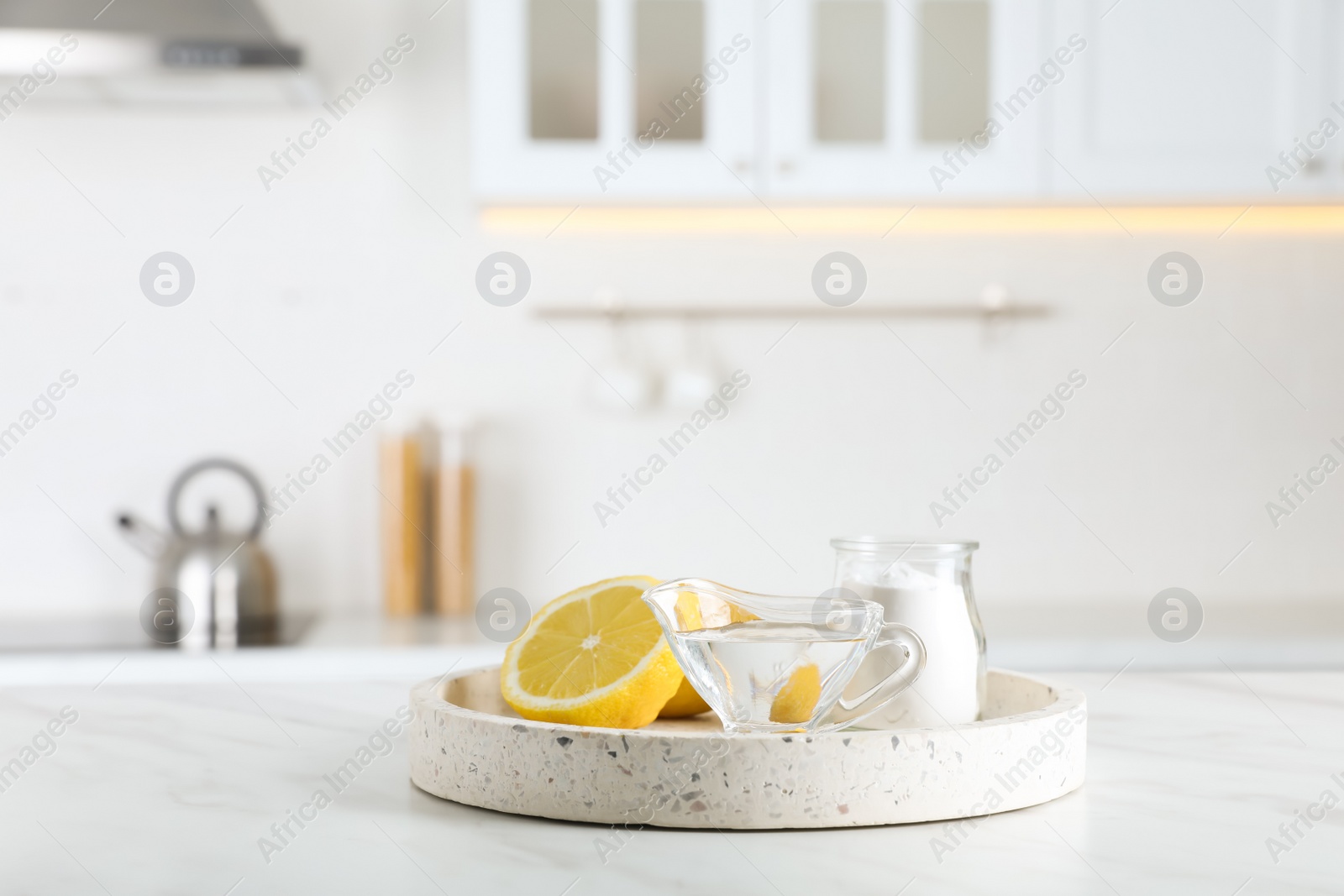 Photo of Vinegar, baking soda and lemon on white marble table in kitchen. Eco friendly natural detergents