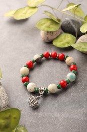 Photo of Beautiful bracelet with gemstones, leaves and stones on grey background