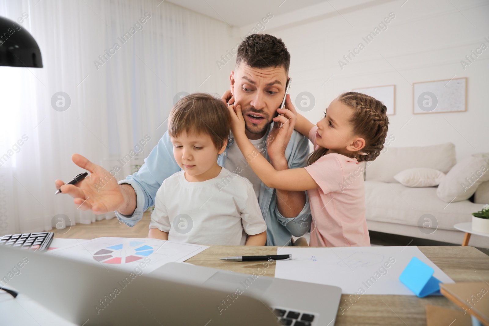 Photo of Overwhelmed man combining parenting and work at home