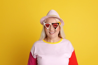 Portrait of mature woman in hipster outfit on color background