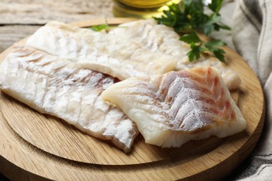 Photo of Fresh raw cod fillets and parsley on wooden table, closeup