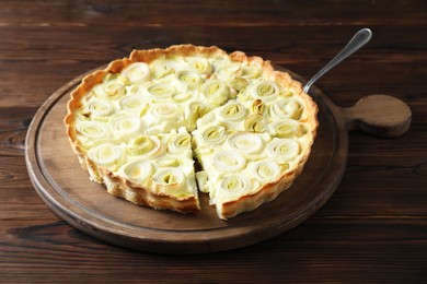 Photo of Board with tasty leek pie and cake server on wooden table, closeup