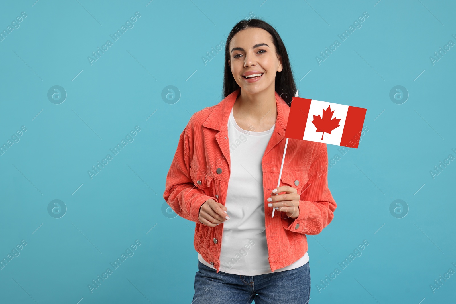 Image of Happy young woman with flag of Canada on light blue background