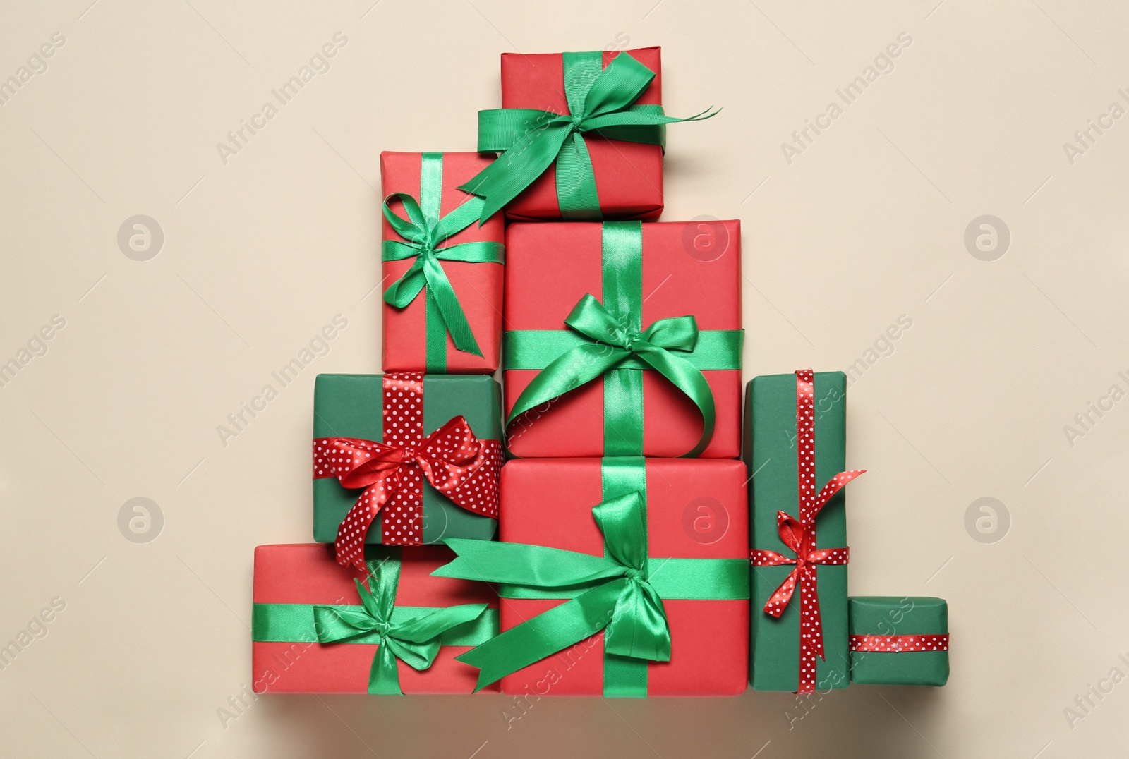 Photo of Christmas tree shape of gift boxes on beige background, flat lay