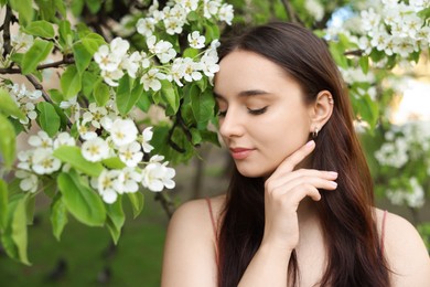 Beautiful woman near blossoming tree on spring day