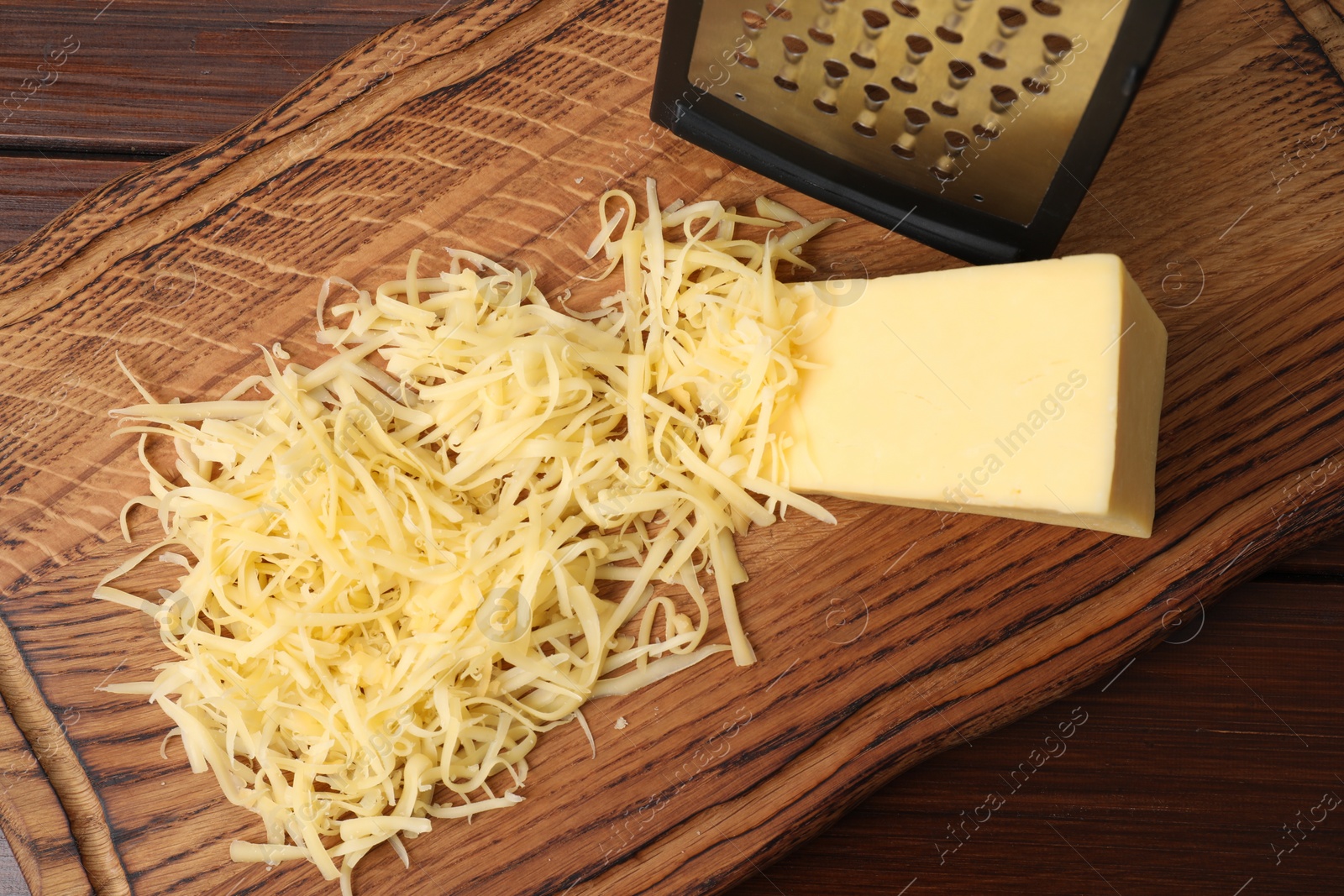 Photo of Grated and whole piece of cheese on wooden table, top view