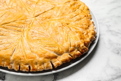 Traditional galette des rois on white marble table, closeup