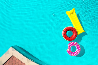 Image of Inflatable rings and mattress floating in swimming pool, top view with space for text. Summer vacation