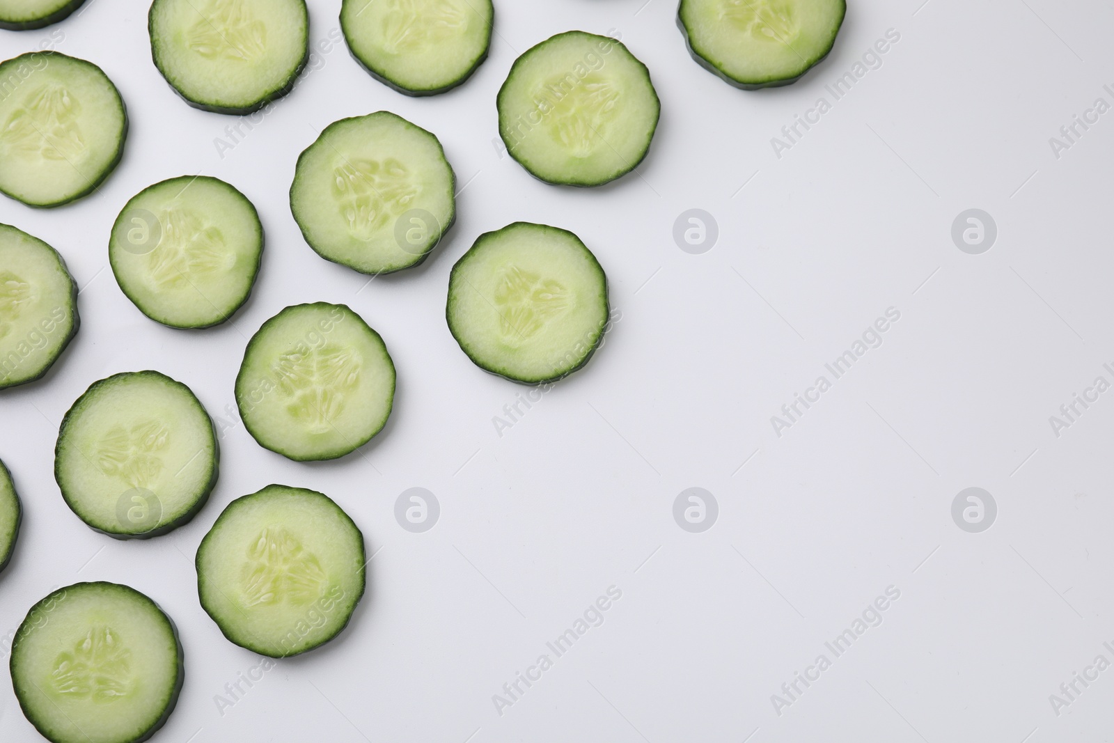 Photo of Fresh slices of cucumbers on white background, top view. Space for text