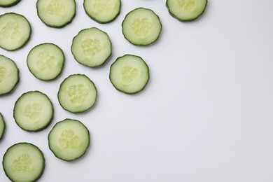 Fresh slices of cucumbers on white background, top view. Space for text