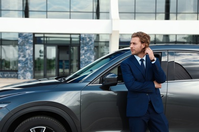 Photo of Attractive young man near luxury car outdoors