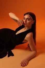 Photo of Beautiful woman in black dress posing on brown background